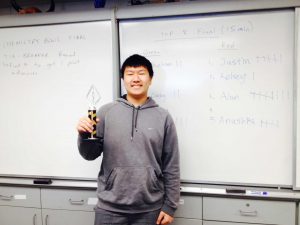 Sophomore Alan Tan poses with trophy in front of scoreboard