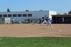 Christina Martin pitching to the Newark Memorial Cougars as Dahlen Dennis, third base, and Jowelle Campbell, first base, watch on.