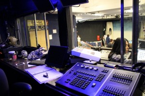 The interior of the sound booth behind Julian Chan at the sound board. 