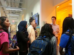 Girls in STEM students watching scientists in the clean room.