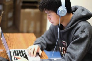 Senior Joshua Tso listens to and analyzes his latest composition for orchestra (Photo: Cathy Wang).