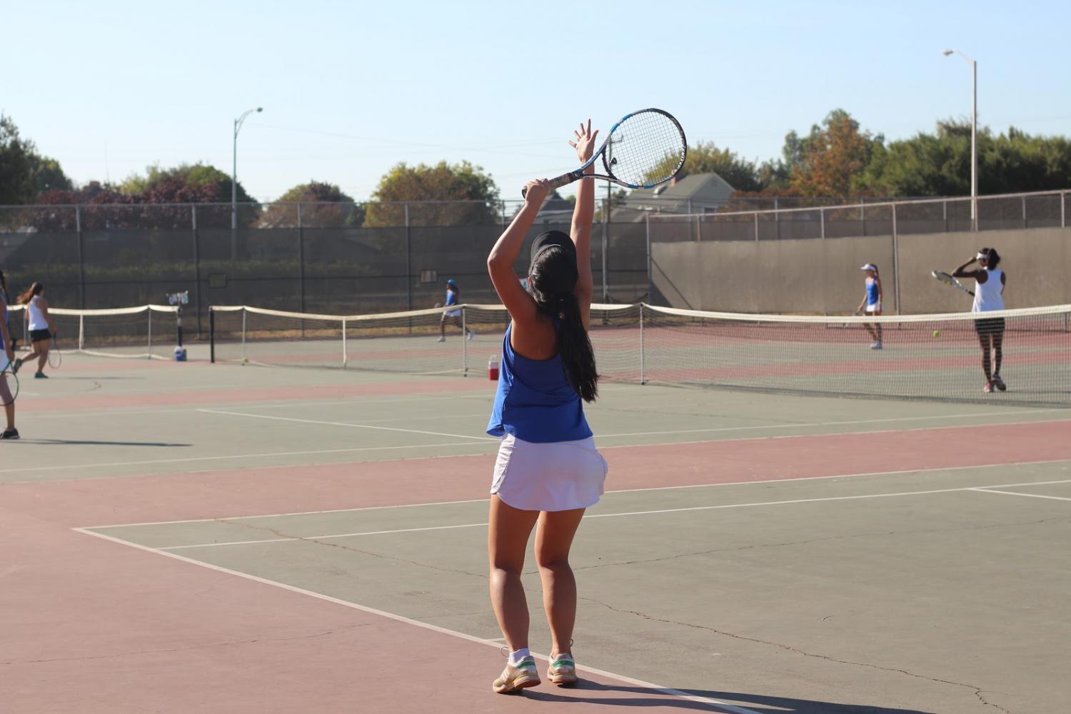 Varsity+member+Amanda+Tran+%2812%29+prepares+to+serve+in+her+singles+game.+