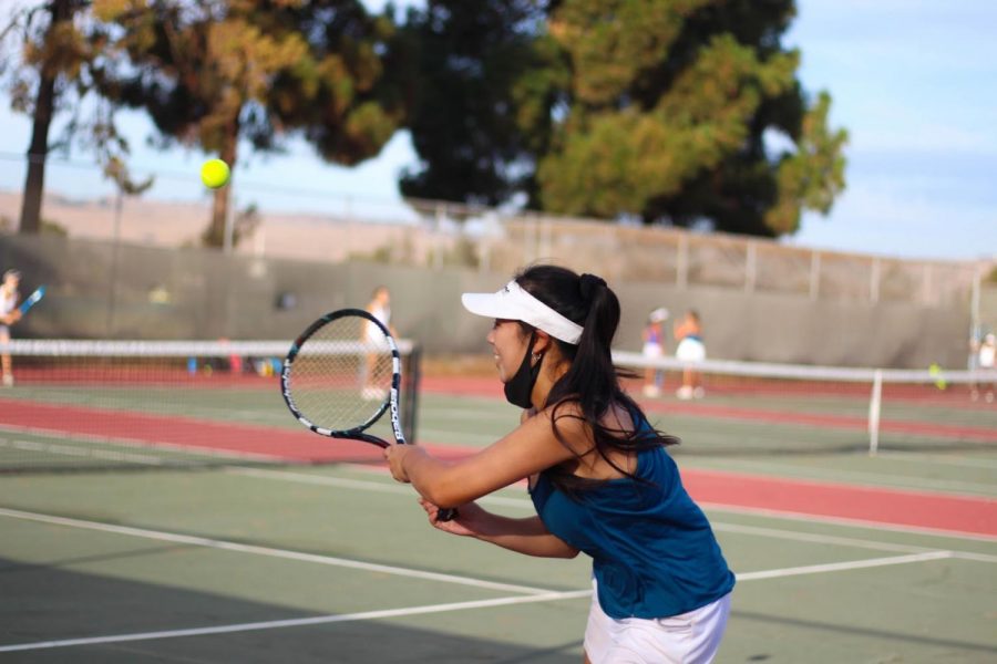 Captain Arista Zhu (12) smiles as she executes a double-handed backhand swing. 