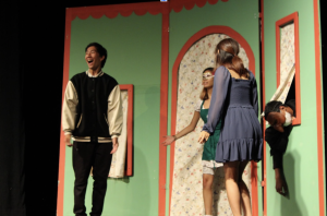 The Male Lover (Kyle Peng) gets excited as he proposes to the Female Lover (Skye Baoung) while his servant Punchanella (Sri Sankar) lies dead in the window and Columbina (Kat Tiana) warns the lovers that the house is on fire.