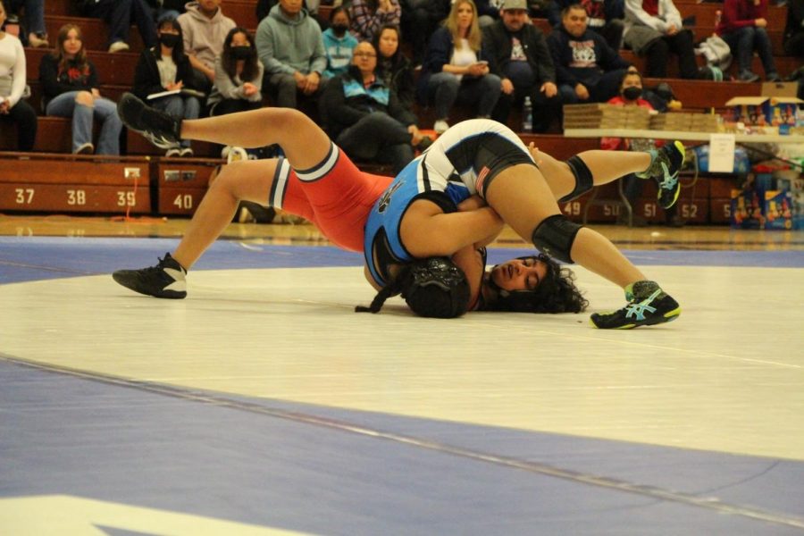 Fourth-year wrestler Jawahar (blue) takes down her opponent (red), winning her match.
