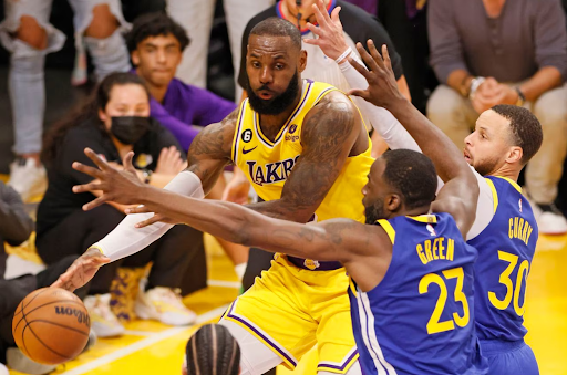 Los Angeles Lakers star LeBron James dribbles past Golden State Warriors players Draymond Green, and superstar Stephen Curry (Fox Sports).