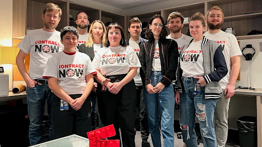 SNL post-production editors wearing shirts written “Contract Now” to show their demand of a contract with NBCUniversal (Vulture).