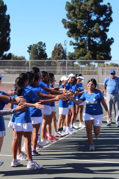 Girls Tennis cheers on their teammate before the game starts.