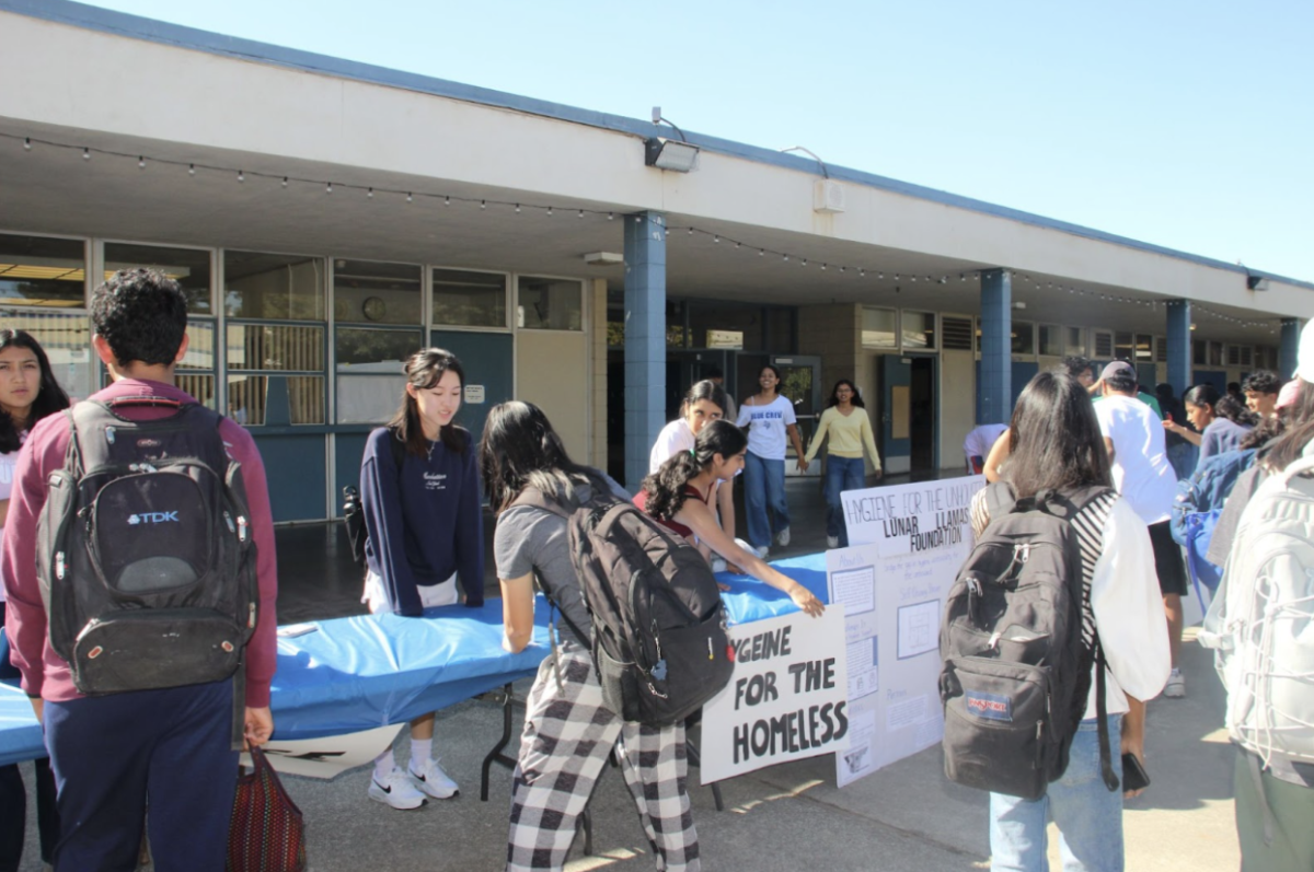 Students stand in front of the booths at the side of the courtyard, discussing with officers from various organizations about the positions they are offering. 