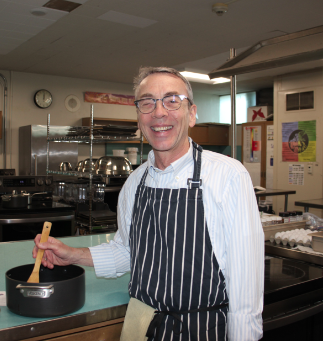 Mr. Rodocker stands in his culinary lab, mixing a pot of food. 
