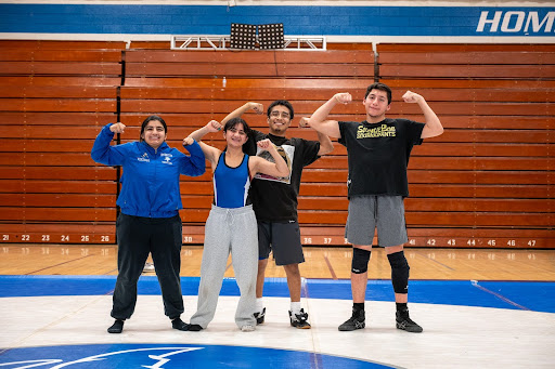 IHS Wrestling seniors pose for a photo with muscles flexed, commemorating years on the wrestling team that will soon come to an end.