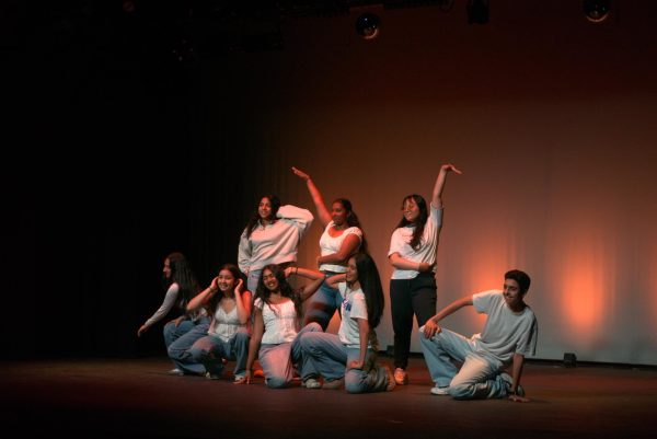 A hip-hop group smiles while holding their final poses at the end of their performance. 
